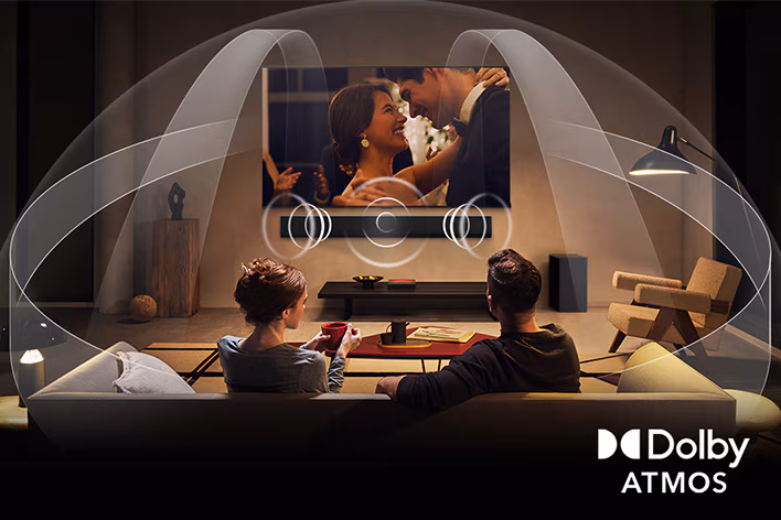 A couple sit in their living room listening to Dolby ATMOS on a wall-mounted LG G5 OLED 4K Smart TV.